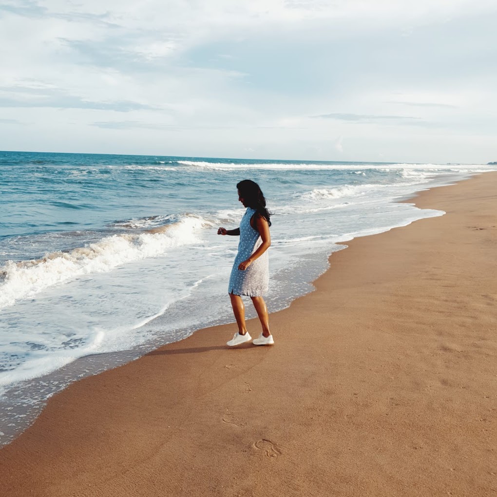 A guest walking along the sandy beach beside ocean waves