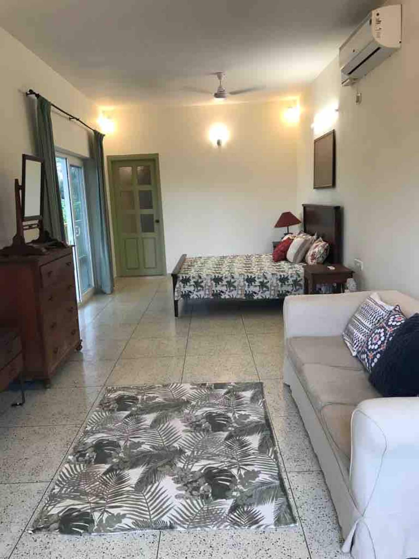 Spacious bedroom at Villa 50 with patterned bedding and garden-facing doors