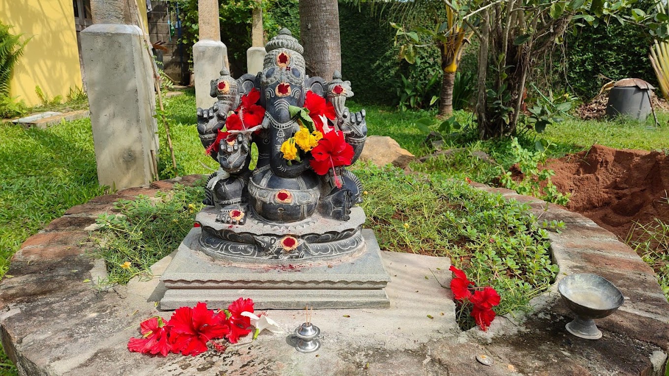 Stone Ganesha statue decorated with red and yellow flowers in the Villa 50 garden